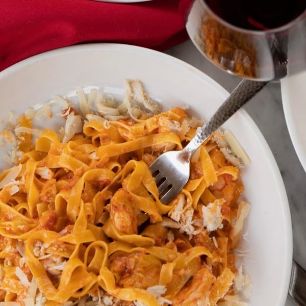 Close-up of Uncommon Grill's fettuccine pasta with red sauce, crab meat, and parmesan cheese.