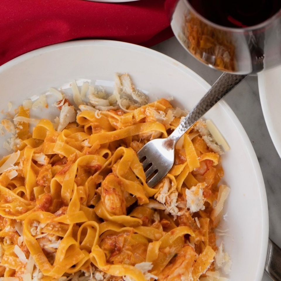 Close-up of Uncommon Grill's fettuccine pasta with red sauce, crab meat, and parmesan cheese.