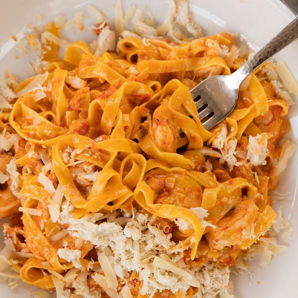 Close-up of fettuccine pasta with red sauce, shrimp, and shredded cheese, with a fork.