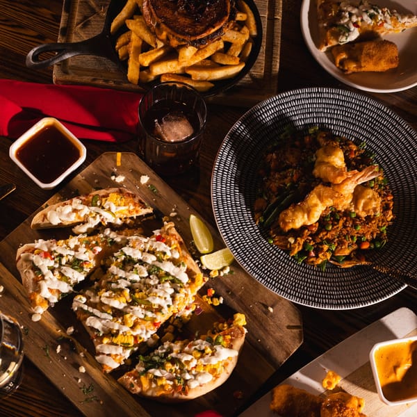 Overhead view of a table laden with various dishes, including pizza, fries, fried rice, and drinks.
