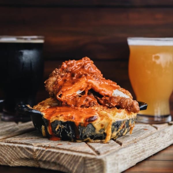 Uncommon Grill's fried chicken and mac and cheese in a skillet, with two beers.