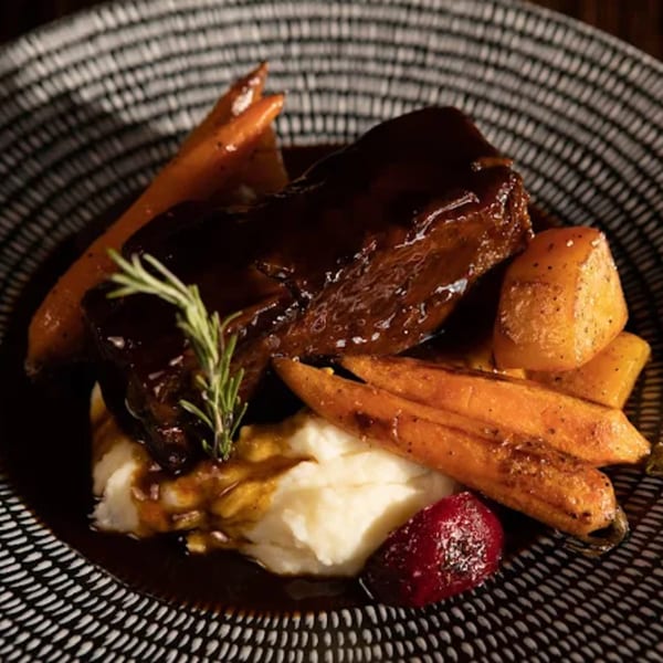 Uncommon Grill's braised short rib with mashed potatoes, roasted carrots, and a sprig of rosemary.