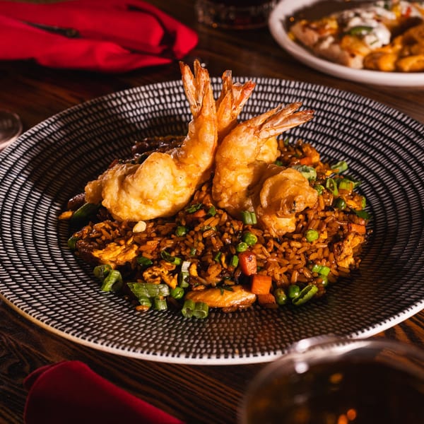 Golden fried shrimp tempura on a bed of savory fried rice with vegetables and scallions.