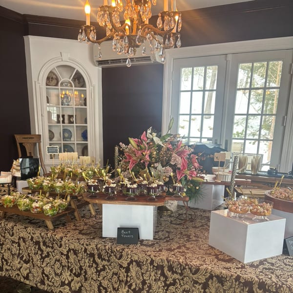 Elegant buffet table with various appetizers, including salads and desserts, in a formal dining room.