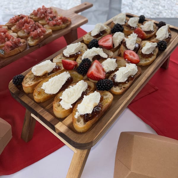 Sweet bruschetta with cream, berries, and jam, alongside savory tomato bruschetta on wooden boards.