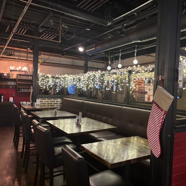 Cozy Uncommon Grill dining area with dark wood tables, leather booths, and festive string lights.