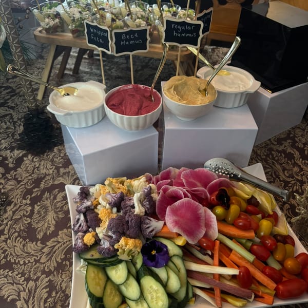 A vibrant Uncommon Grill appetizer spread with various dips, fresh vegetables, and mini salad cups.