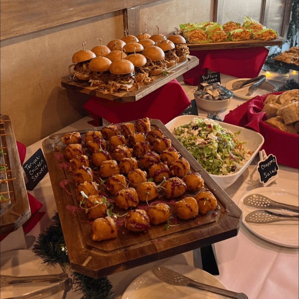 A buffet spread with pulled pork sliders, buffalo chicken lettuce wraps, fried appetizers, and chopped salad.