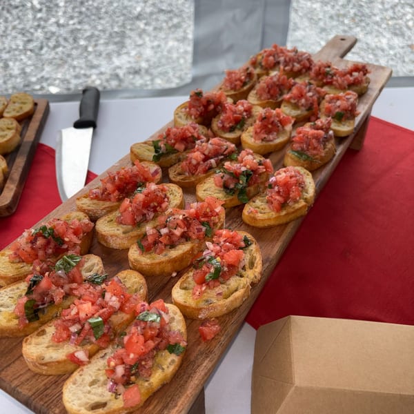 Numerous bruschetta appetizers with diced tomatoes and basil on toasted bread, arranged on a wooden board.